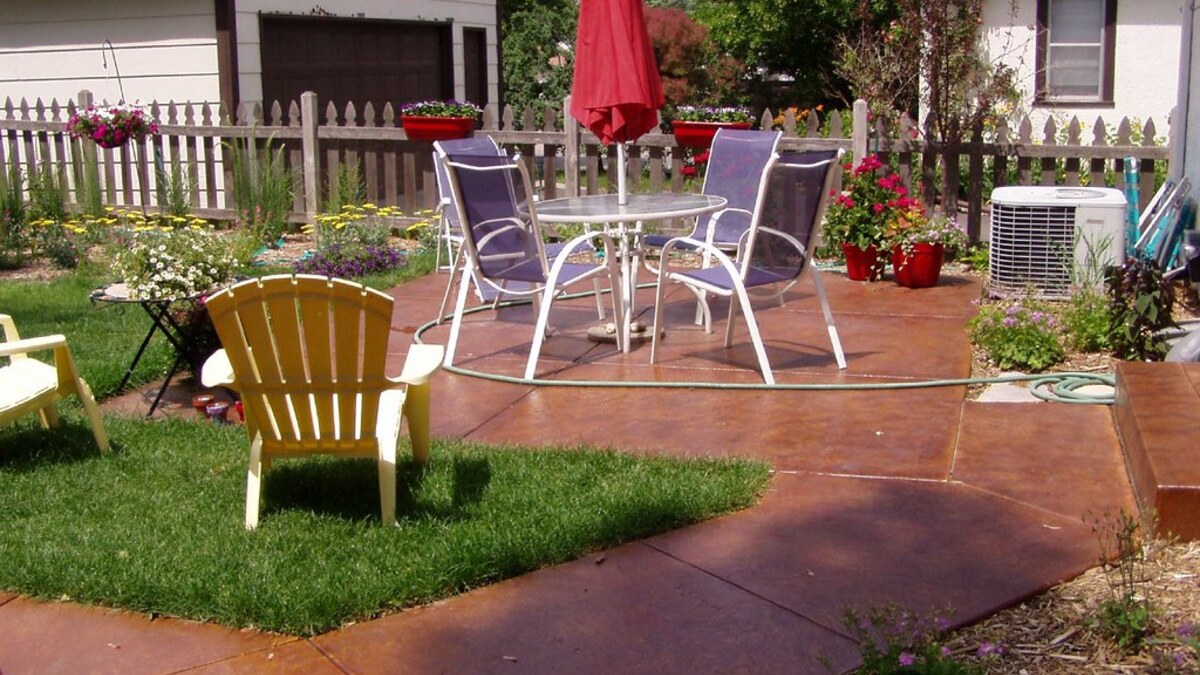 Terrasse en béton aménagée devant une maison avec mobilier de jardin