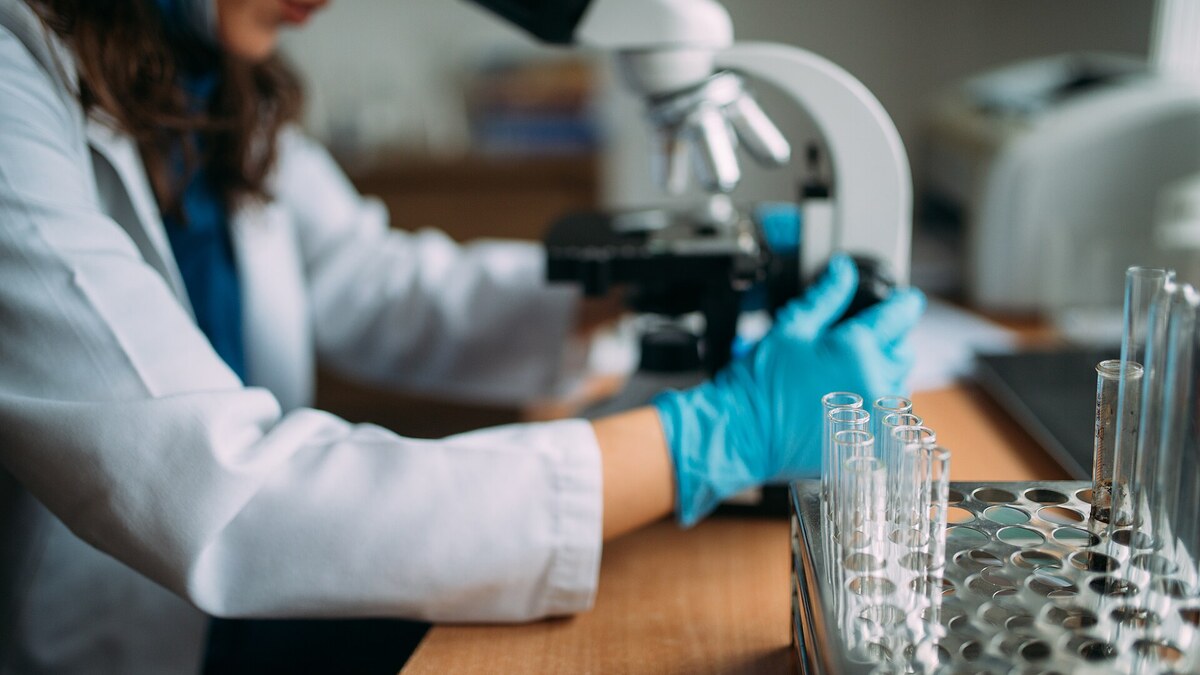 Professionnelle de santé utilisant un microscope dans un laboratoire