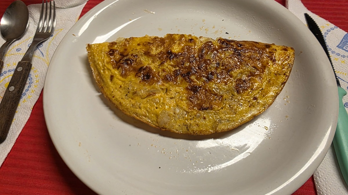 Omelette dorée servie dans une assiette, idée de recette pour utiliser des œufs entiers