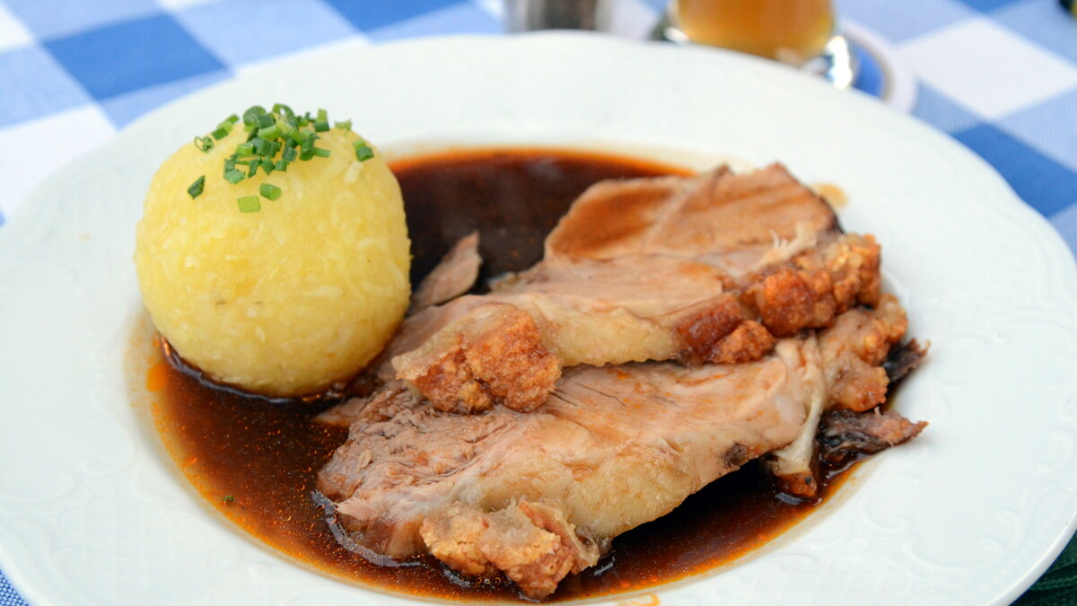 Rôti de porc servi en tranches avec son jus et une garniture de pommes de terre