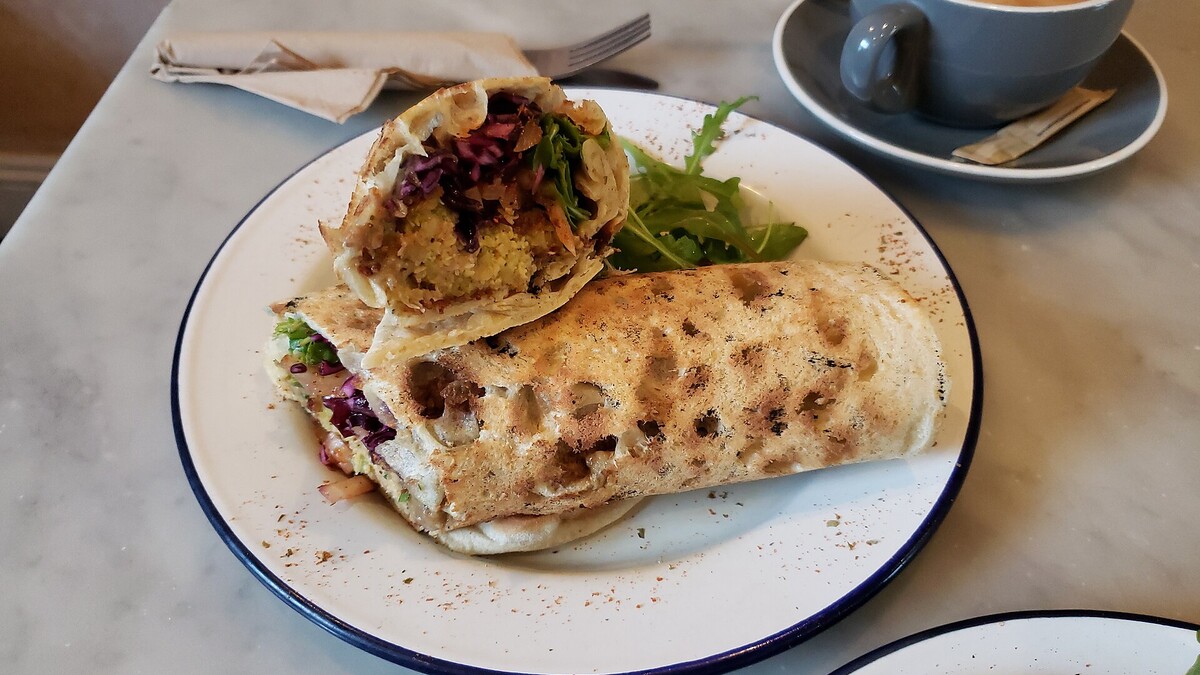 Falafels garnis servis dans un pain plat, accompagnés d’une sauce crémeuse au tahini